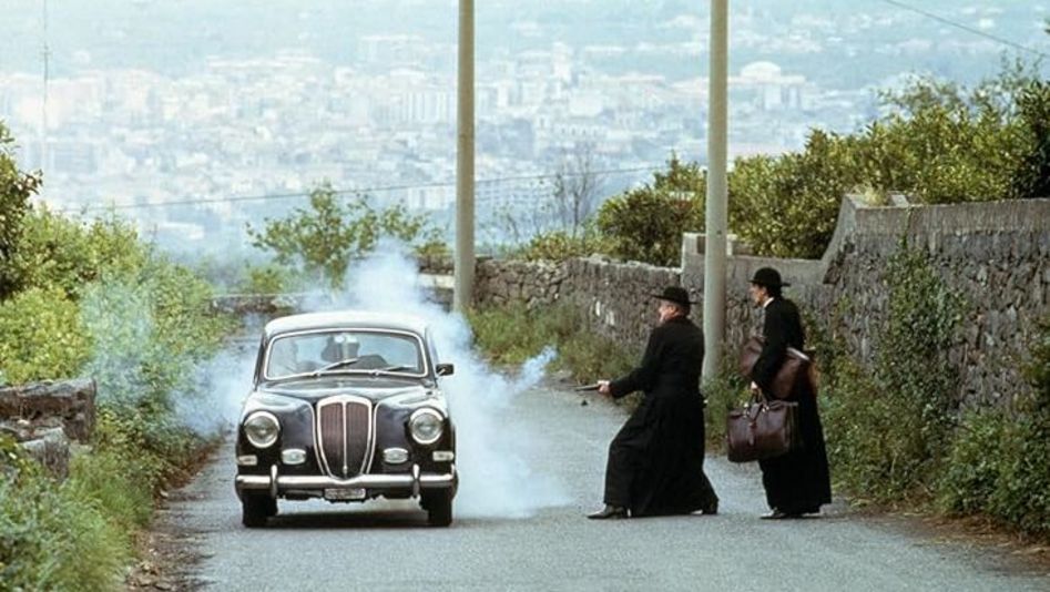 Film still from THE GODFATHER PART III: Two men in clerical robes shoot at a car.