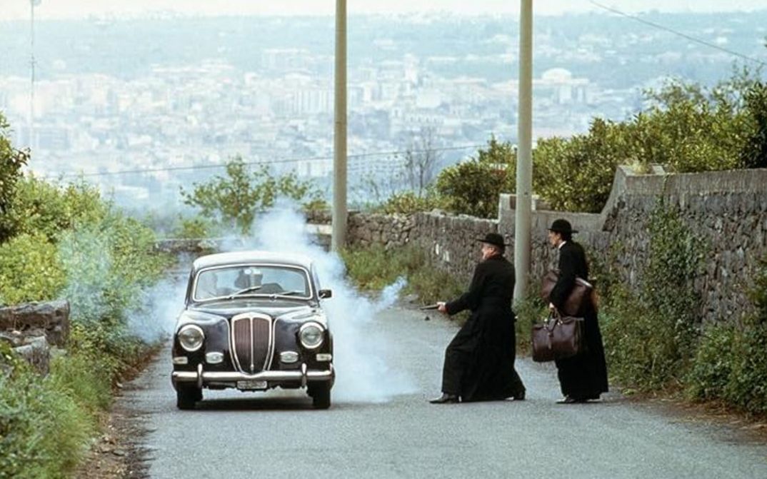 Filmstill aus THE GODFATHER PART III: Zwei Männer in klerikalen Gewändern schießen auf ein Auto.