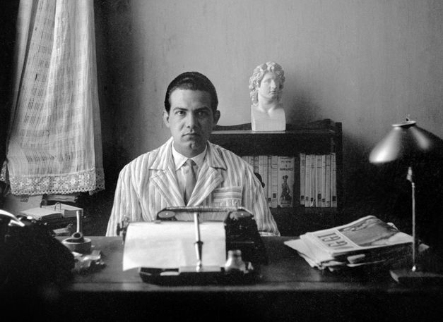 Filmstill aus "Il cassetto segreto" von Costanza Quatriglio. zu sehen ist ein Schwarz-Weiß-Bild eines Mannes mit gegeltem Haar an einem Schreibtisch mit einer Schreibmaschine.