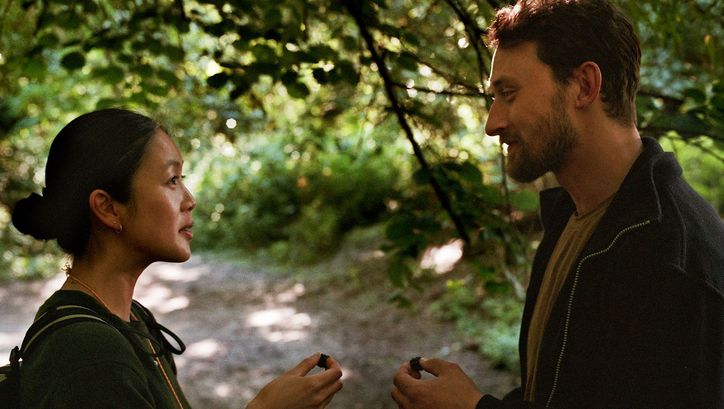 Filmstill aus HERE: Zwei Menschen schauen sich an, sie stehen in einem Wald.