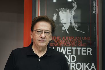 Porträt von Rashid Nugmanov vor Filmposter