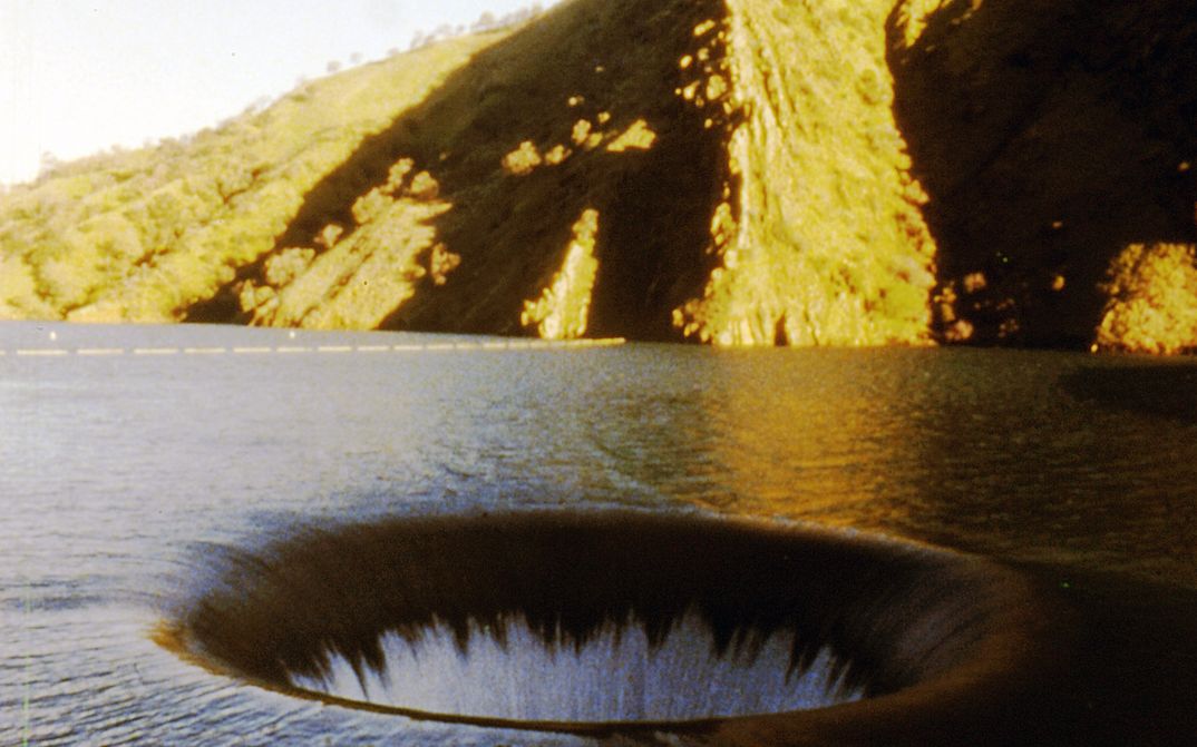 Filmstill aus EL VALLEY CENTRO: Man sieht einen See mit einem Wasserloch.