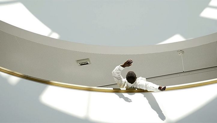 Still from the Film "Jail Bird in a Peacock Chair" by James Gregory Atkinson. A man leans backwards over a railing.
