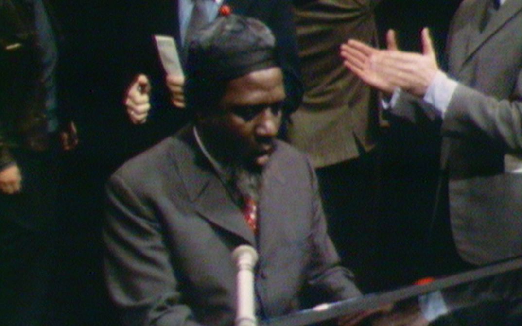 Film still from REWIND AND PLAY: Thelonious Monk is playing the piano. In the background you can see applauding people.