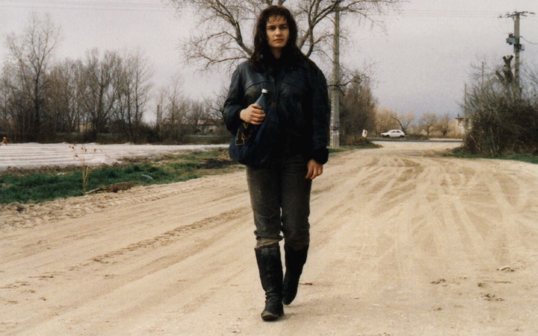 Film still from SANS TOIT NI LOI. A young woman is walking down a street.