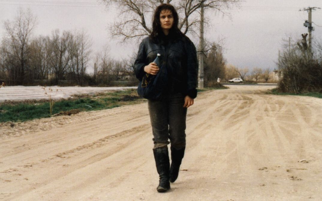 Film still from SANS TOIT NI LOI. A young woman is walking down a street.