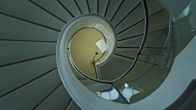 Still from the film "Voices and Shells" by Maya Schweizer. A spiral staircase from above.