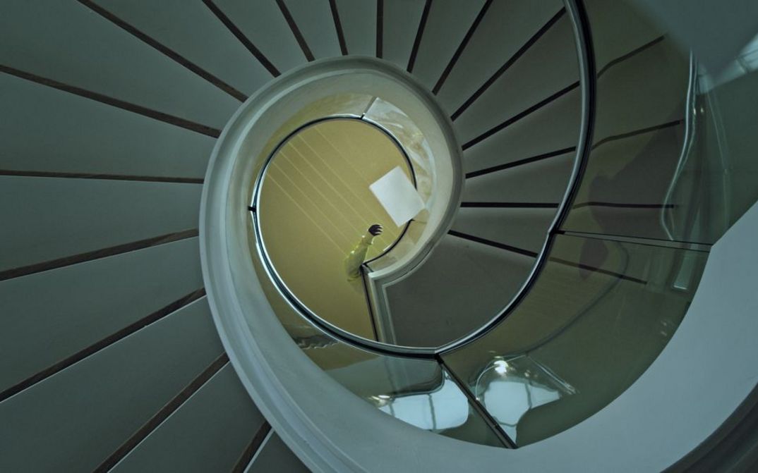 Filmstill aus dem Film "Voices and Shells" von Maya Schweizer. Man sieht eine Wendeltreppe von oben.