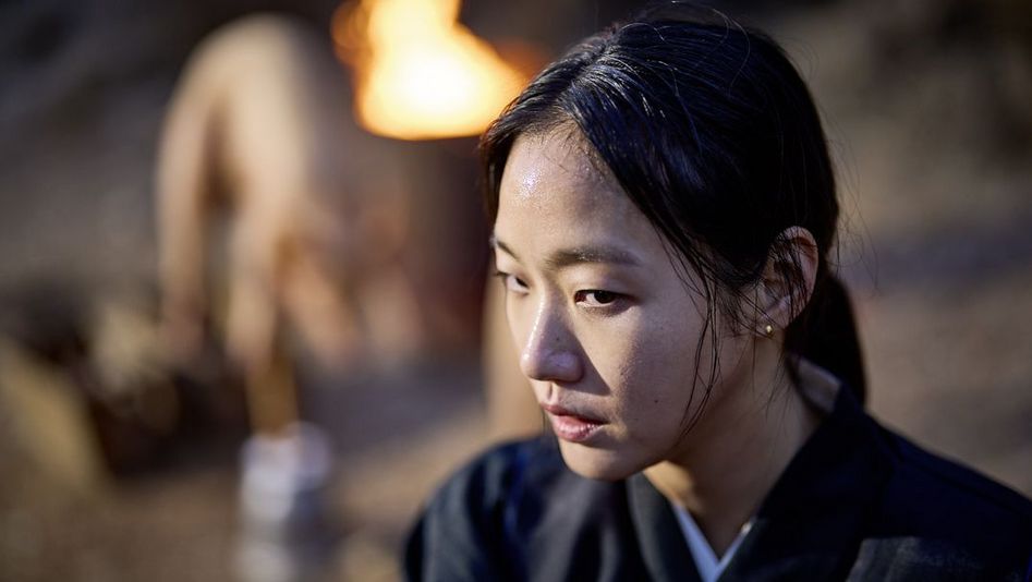 Film still from "Pa-myo" by Jang Jae-hyun. It shows a close-up of a woman with her hair tied back and ear studs. 