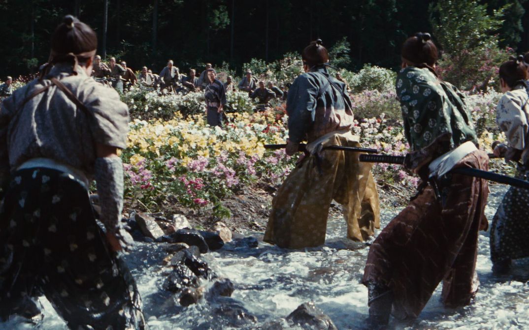 Filmstill aus KENKI: An einem mit vielen Blumen bewachsenen Flussufer steht ein Samurai einer ganzen Reihe von Gegnern gegenüber.